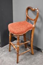 A Victorian correction chair of mixed woods, having balloon and rail back, with later upholstered