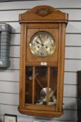 A 1930's oak cased wall clock with silvered dial.