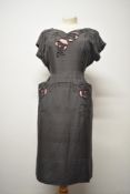 A wonderfully tailored American dress in grey and pink, having cut out detailing with raised