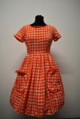 A textured medium weight cotton 1950s day dress, having orange and white dog tooth pattern, patch