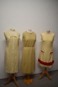 Three vintage 1960s dresses, one mid length metallic dress, a red and cream wool mini dress and a
