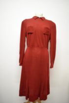 A russet coloured 1940s day dress, having long sleeves, pockets to bodice with angular stitched