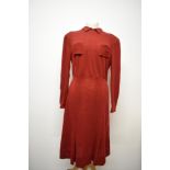 A russet coloured 1940s day dress, having long sleeves, pockets to bodice with angular stitched