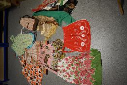 An assortment of bright mid century full aprons and half aprons and some vintage scarves.