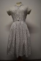 A 1950s cotton day dress, having pleated skirt, side metal zip and buttons to front, Swiss label