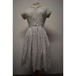 A 1950s cotton day dress, having pleated skirt, side metal zip and buttons to front, Swiss label