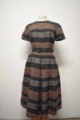 A late 1950s / 1960s day dress, having pleats to skirt, short sleeves and matching belt.