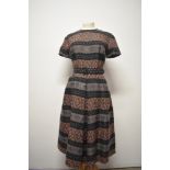 A late 1950s / 1960s day dress, having pleats to skirt, short sleeves and matching belt.