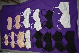 Fourteen vintage 1940s and 50s bras, some multiples of the same style in black and white, others