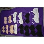 Fourteen vintage 1940s and 50s bras, some multiples of the same style in black and white, others