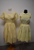 Two 1950s yellow day dresses, one of sheer floaty fabric, having embroidery to bodice and pleats