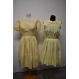 Two 1950s yellow day dresses, one of sheer floaty fabric, having embroidery to bodice and pleats