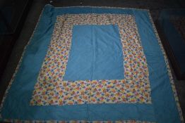 A vintage floral quilt, block floral to one side and the other having border of blue, feels to be