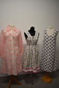 Three 1960s dresses, one linen with bright floral patterns, another of cotton with purple rose