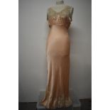 An Art Deco pale pink bias cut nightdress, having beautiful lace to bodice and hem, tie fastening to