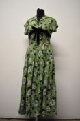 A pea green 1940s cotton day dress, having bold black and white hibiscus pattern, with full