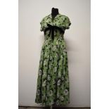 A pea green 1940s cotton day dress, having bold black and white hibiscus pattern, with full