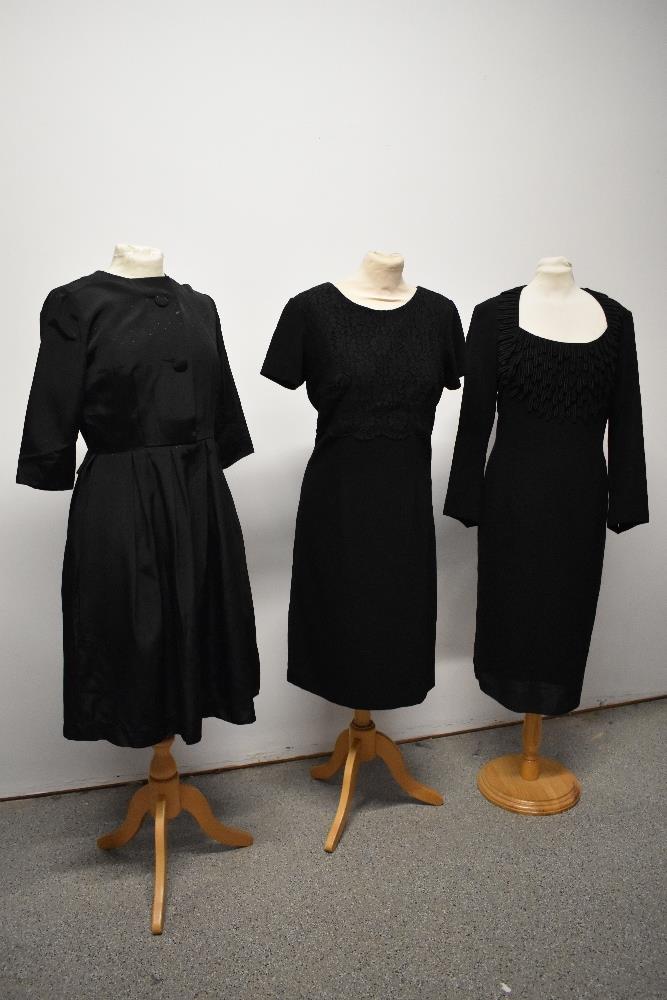 A 1950s black dress with pleated skirt and two 1960s wiggle dresses.