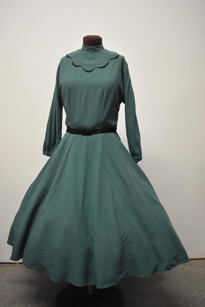 A 1950s green day dress, having black scalloped detail to bodice, high collar, long sleeves, full