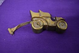 An Edwardian brass measuring tape in the form of a car.