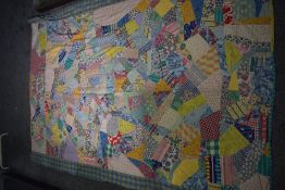 A vintage bed throw, using colourful patches of random form, predominantly 1940s and 50s fabrics