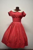 A 1950s red cotton day dress, having delicate flower and bow pattern, buttons to front, white