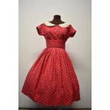 A 1950s red cotton day dress, having delicate flower and bow pattern, buttons to front, white