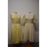 Two pale yellow 1950s day dresses, one of textured cotton and the other a synthetic semi sheer