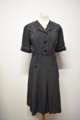 A dark navy blue medium weight cotton day dress with white polka dots, having piped detailing in