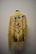 An early 20th century yellow shawl, having deep fringe to edge and colourful floral embroidery.