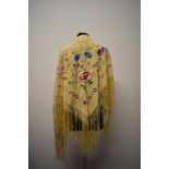 An early 20th century yellow shawl, having deep fringe to edge and colourful floral embroidery.