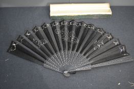An early 20th century black silk fan, having silver sequinned butterflies and silver studs to ribs.