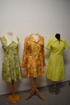 Three bright and cheerful 1960s mini dresses, including two with vibrant floral patterns.