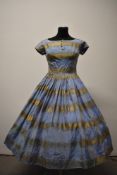 A 1950s blue and gold dress, having full pleated skirt, diamante accents to bodice and rear metal