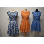 Three floaty abstract patterned day dresses, two having concertina pleats, one with belt.