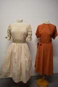 Two vintage dresses, one rust toned dress with rusched bodice and tie belt to waist, side metal
