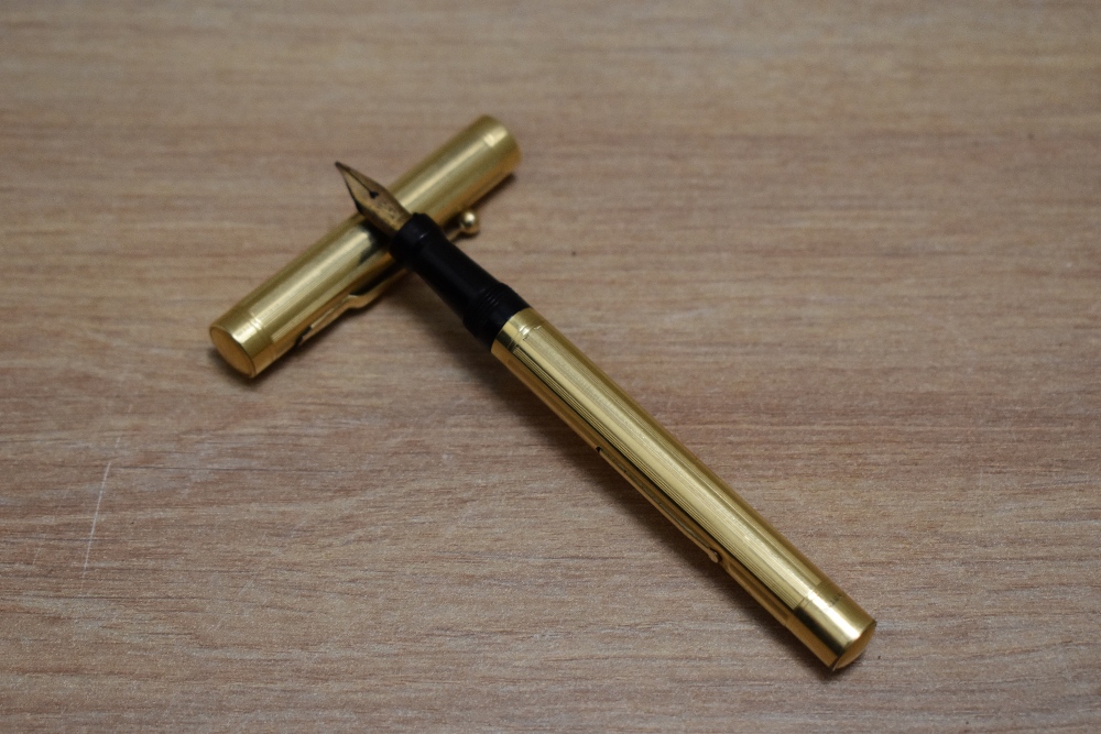 A Mabie Todd Self Filling lever fill fountain pen in yellow metal in engine turned reeded design