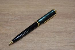 A Pelikan Souveran ballpoint pen with black barrel and green and black striped cap.