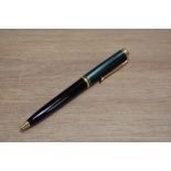 A Pelikan Souveran ballpoint pen with black barrel and green and black striped cap.