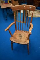 A 19th Century elm armchair of traditional form having spindle back and solid seat