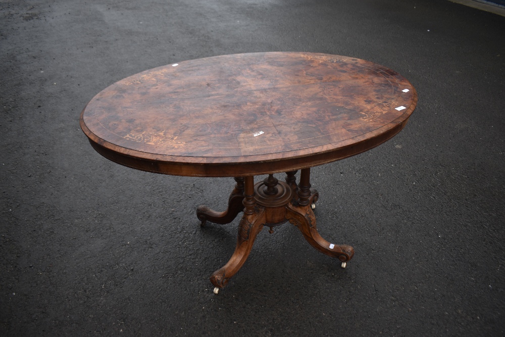 A 19th Century walnut breakfast table having inlaid oval top on quadruple turned column supports and