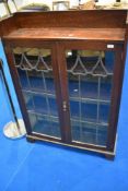 A late 19th or early 20th Century oak bookcase having shaped leaded glass doors, in the Art