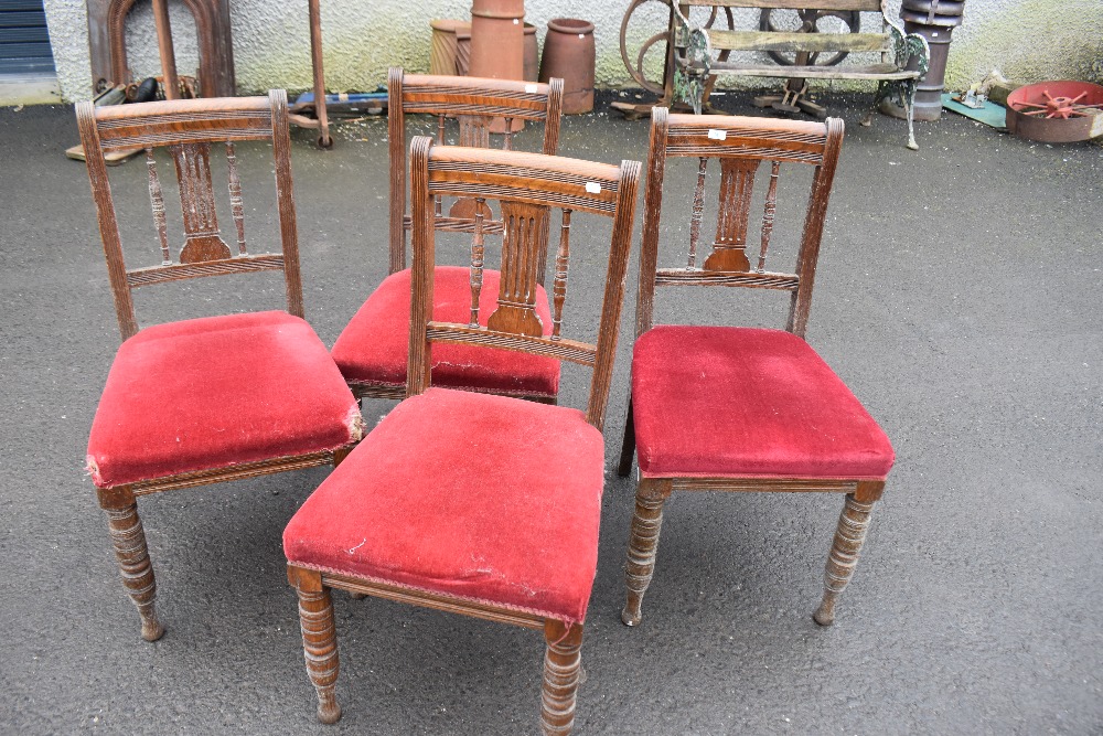 A set of four Victorian oak dining chairs having rail and spindle back, over stuffed seats on turned