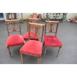 A set of four Victorian oak dining chairs having rail and spindle back, over stuffed seats on turned