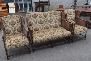 A late 19th or early 20th Century three piece lounge suite having oak twist frae, bergere cane sides