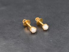A pair of pearl stud earrings, the white pearls set in twenty-two carat gold with screw posts and