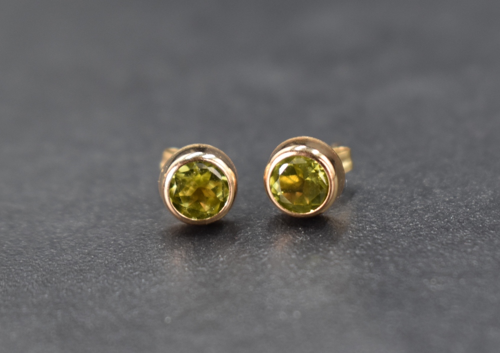 A pair of peridot stud earrings set in 9ct gold bezel settings, 0.5g