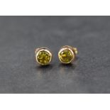 A pair of peridot stud earrings set in 9ct gold bezel settings, 0.5g