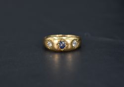 A Victorian three stone 18ct gold band ring having a central sapphire flanked by two diamonds,