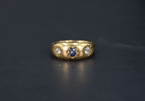 A Victorian three stone 18ct gold band ring having a central sapphire flanked by two diamonds,